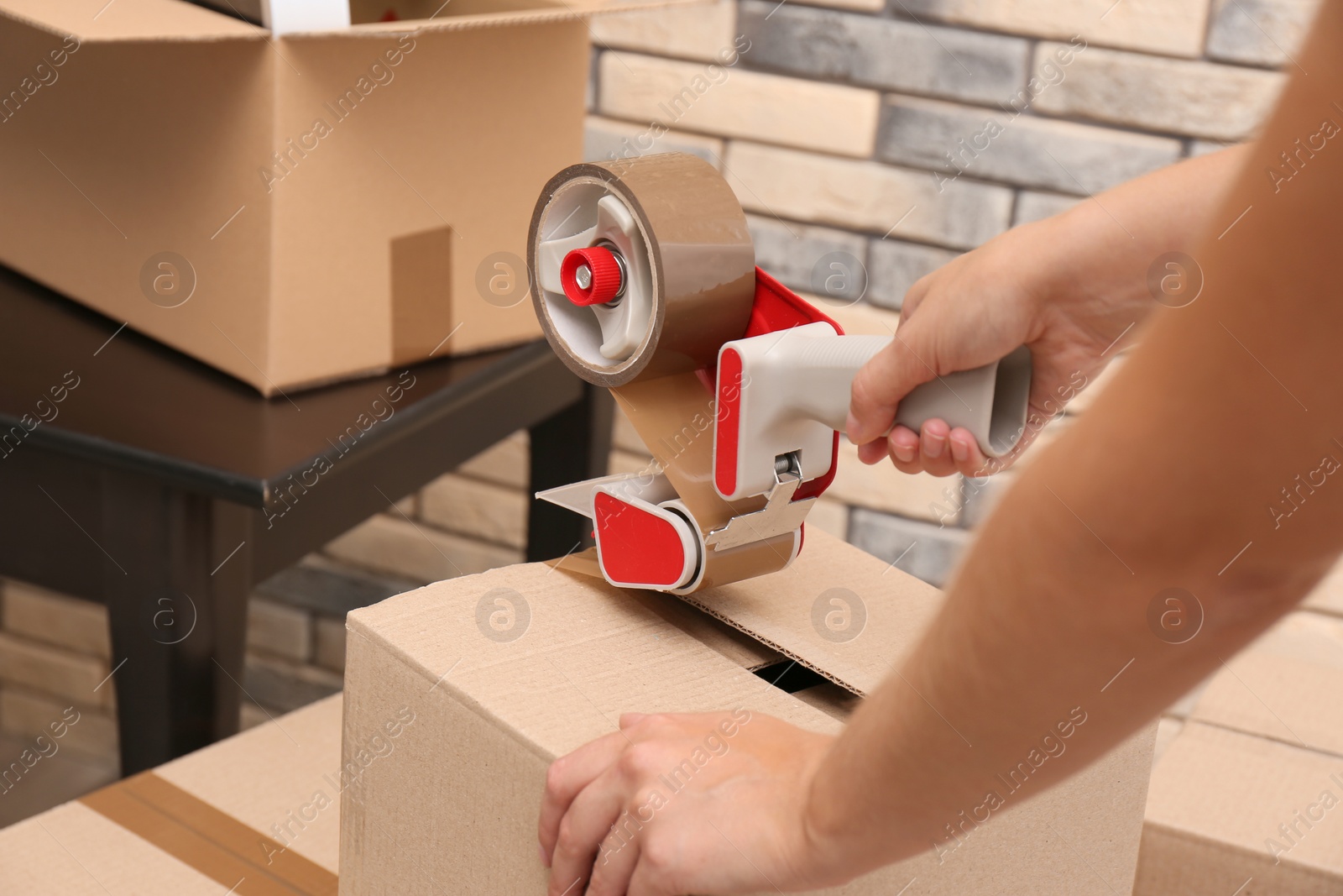 Photo of Woman packing carton box indoors, closeup. Moving day