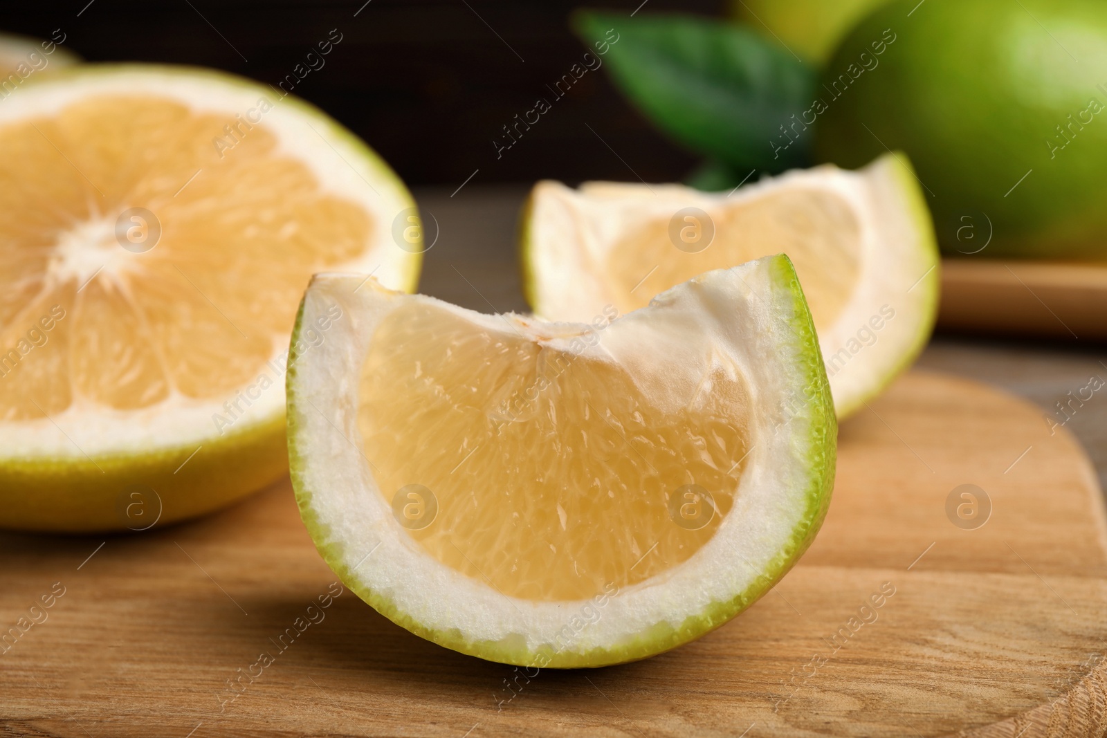 Photo of Cut fresh sweetie fruit on wooden board, closeup