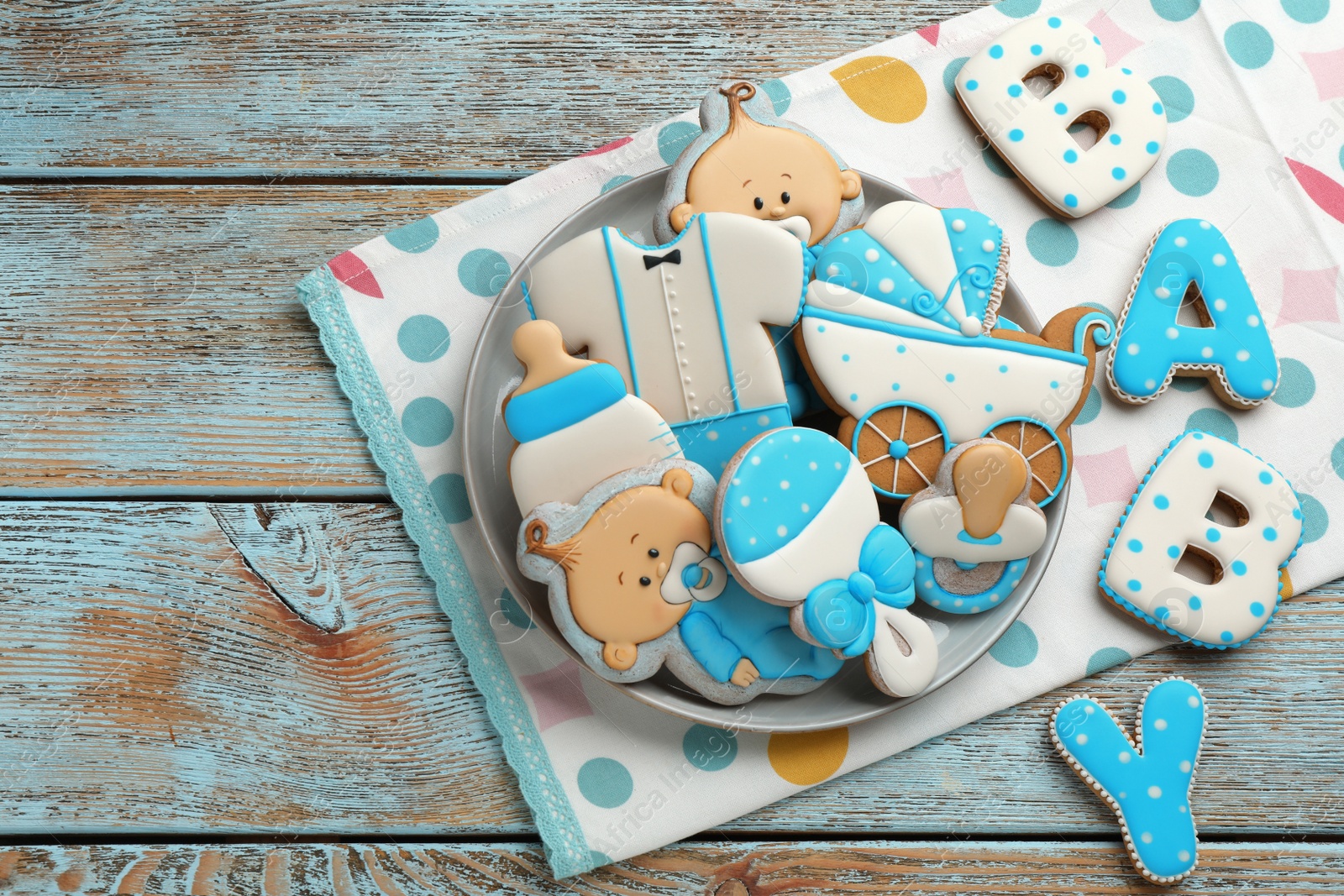 Photo of Word Baby and tasty cookies of different shapes on light blue wooden table, flat lay. Space for text