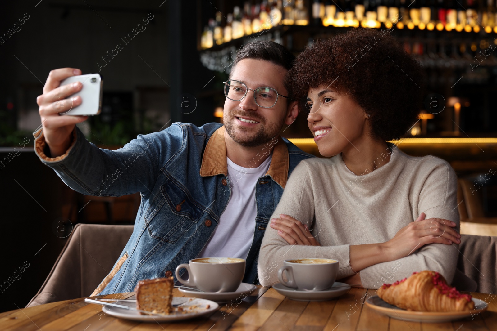 Photo of International dating. Happy couple taking selfie in cafe