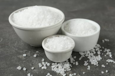 Bowls with natural sea salt on grey table