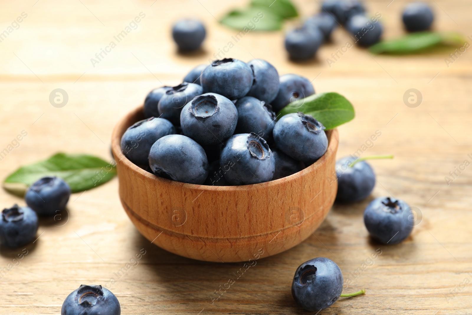 Photo of Bowl of tasty fresh blueberries on wooden table, closeup