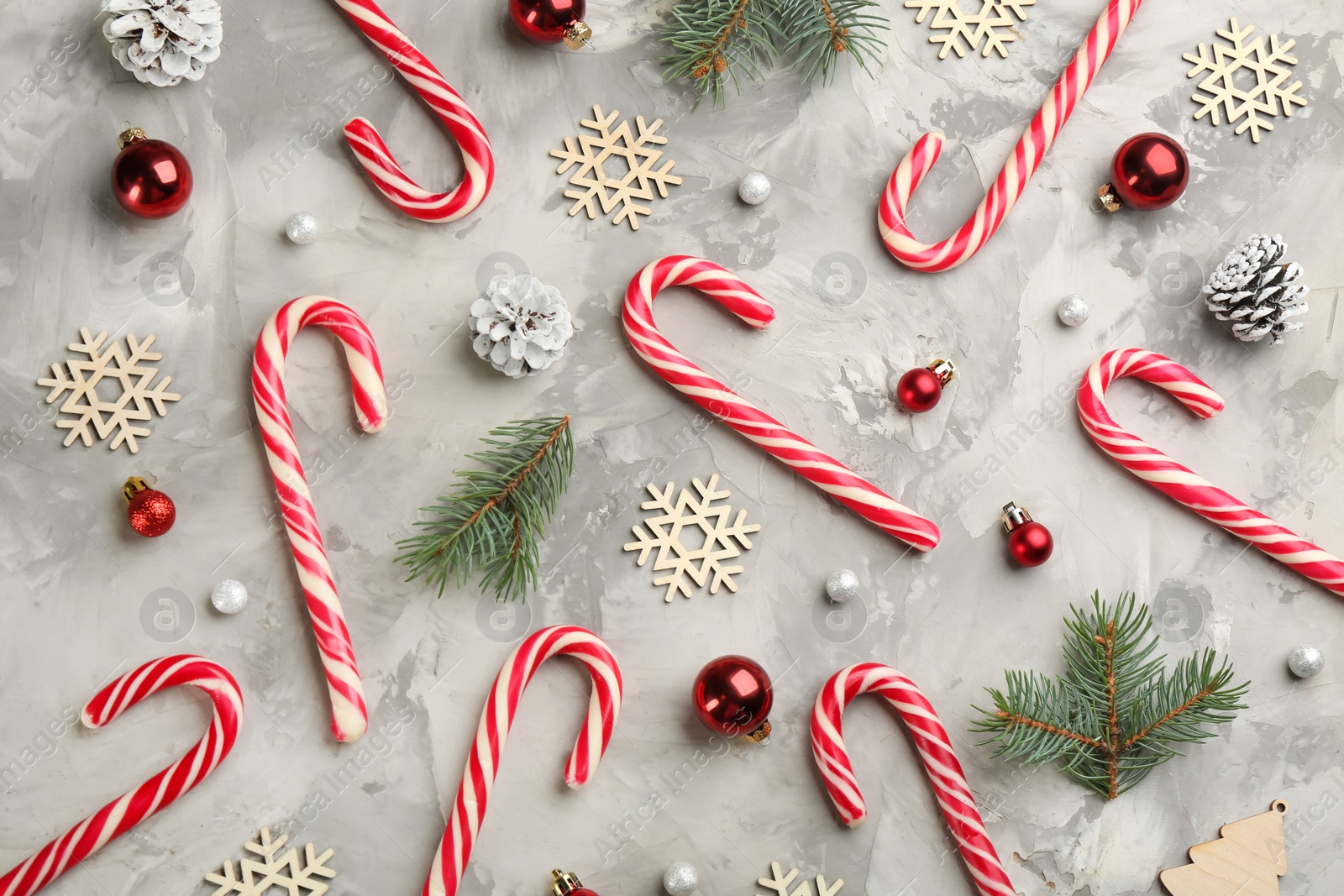 Photo of Flat lay composition with candy canes and Christmas decor on grey table