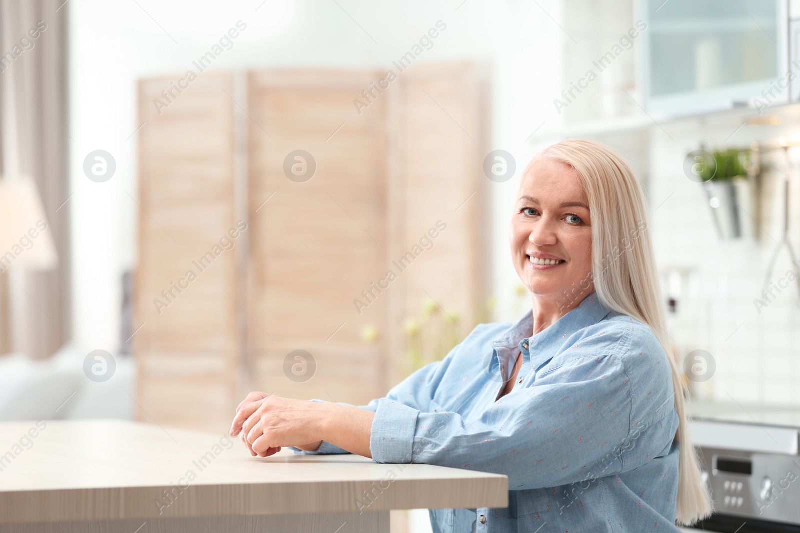 Photo of Portrait of happy mature woman at table indoors