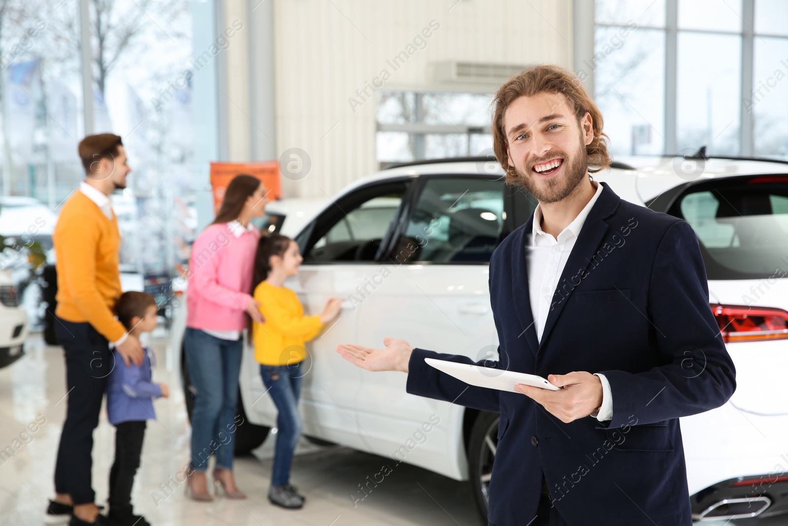 Photo of Car salesman with tablet and blurred family near auto on background