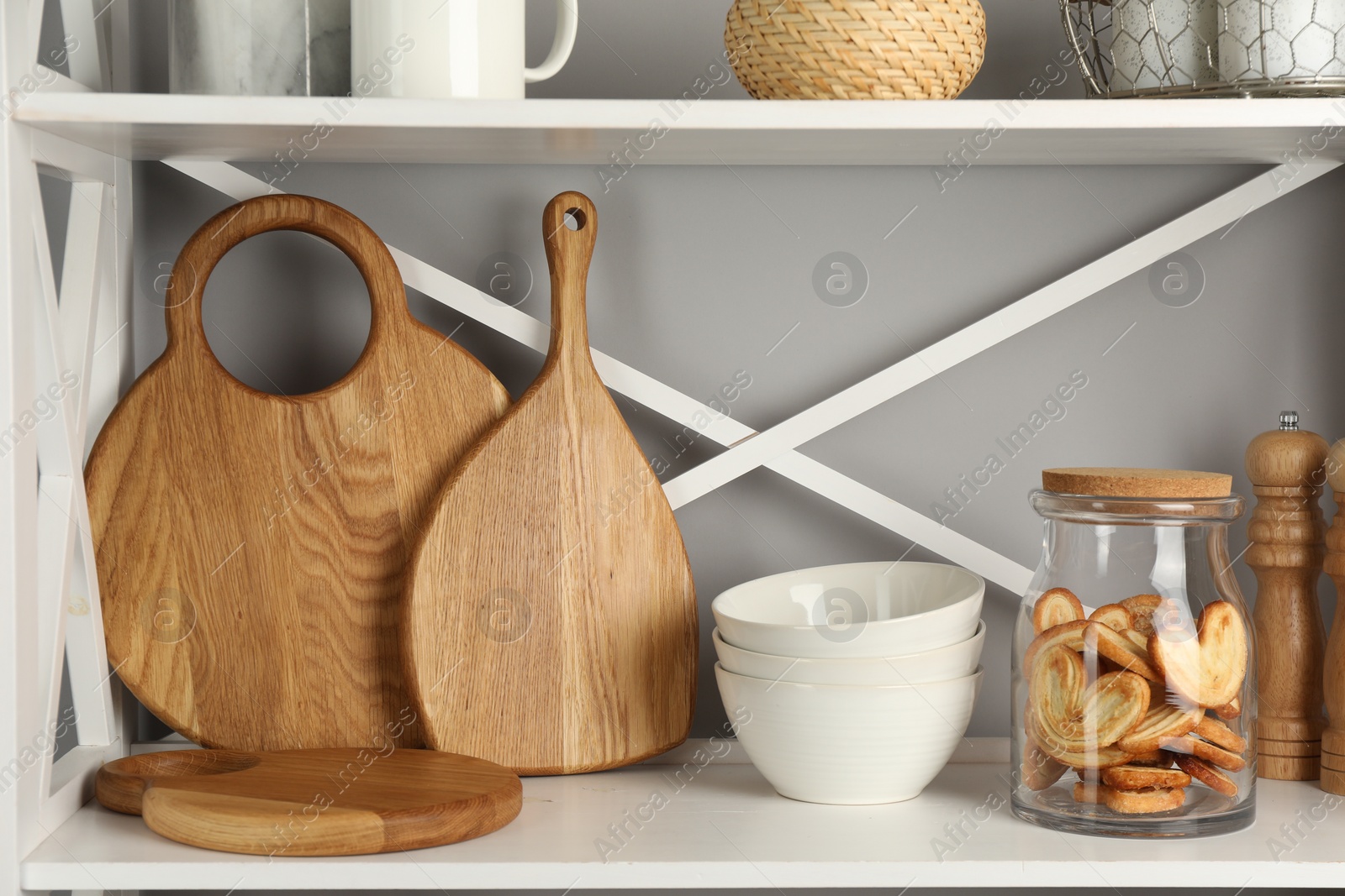 Photo of Wooden cutting boards, bowls and french palmier cookies on shelving unit