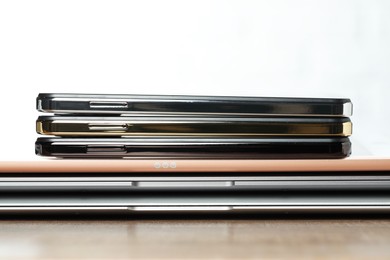 Stack of electronic devices on wooden table, closeup