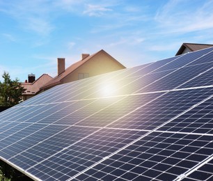 Photo of Solar panels near houses under blue sky on sunny day. Alternative energy source