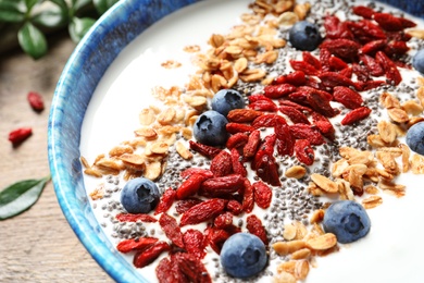 Smoothie bowl with goji berries on wooden table, closeup