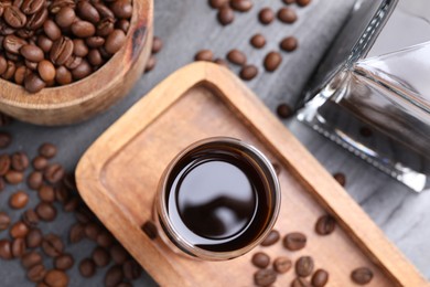 Photo of Coffee liqueur and beans on grey table, flat lay