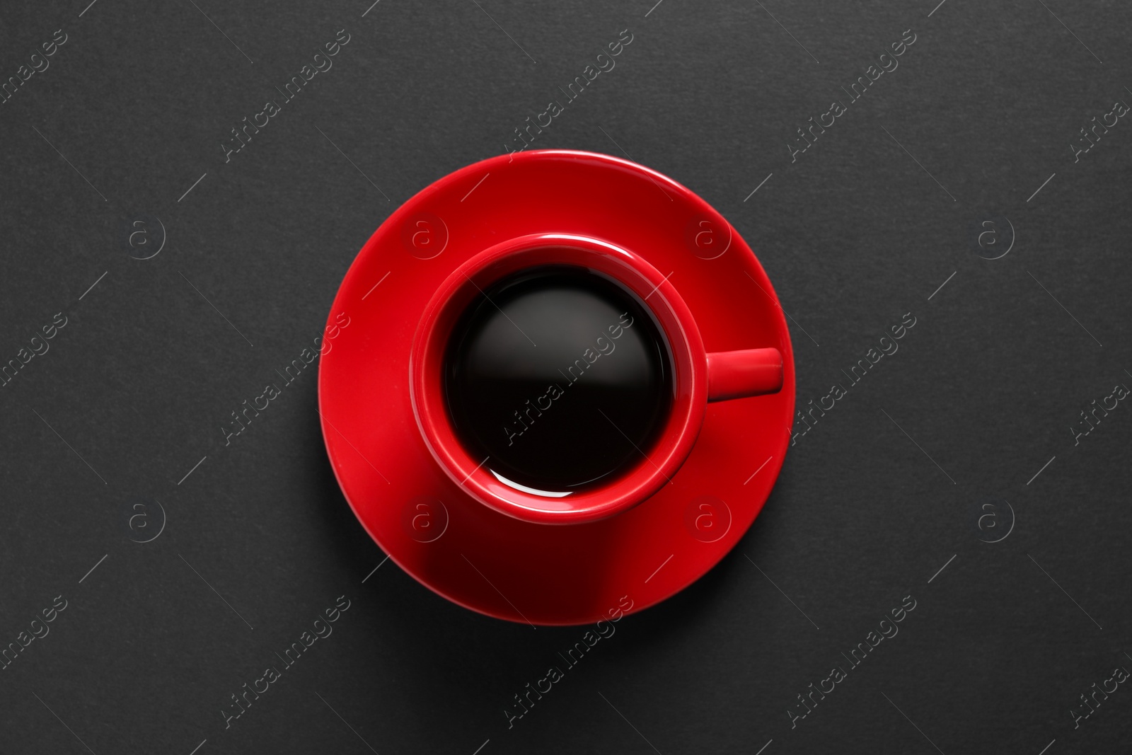 Photo of Red cup with aromatic coffee on black background, top view