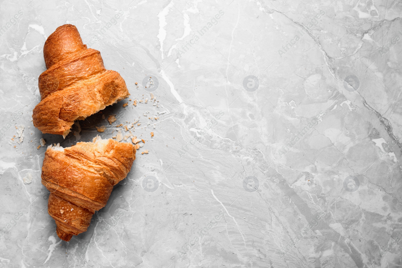 Photo of Tasty fresh croissant on light grey marble table, flat lay. Space for text