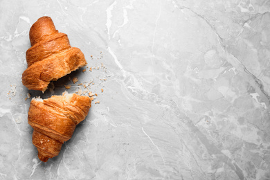 Tasty fresh croissant on light grey marble table, flat lay. Space for text