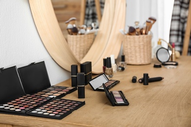 Photo of Cosmetics and brushes on dressing table in makeup room