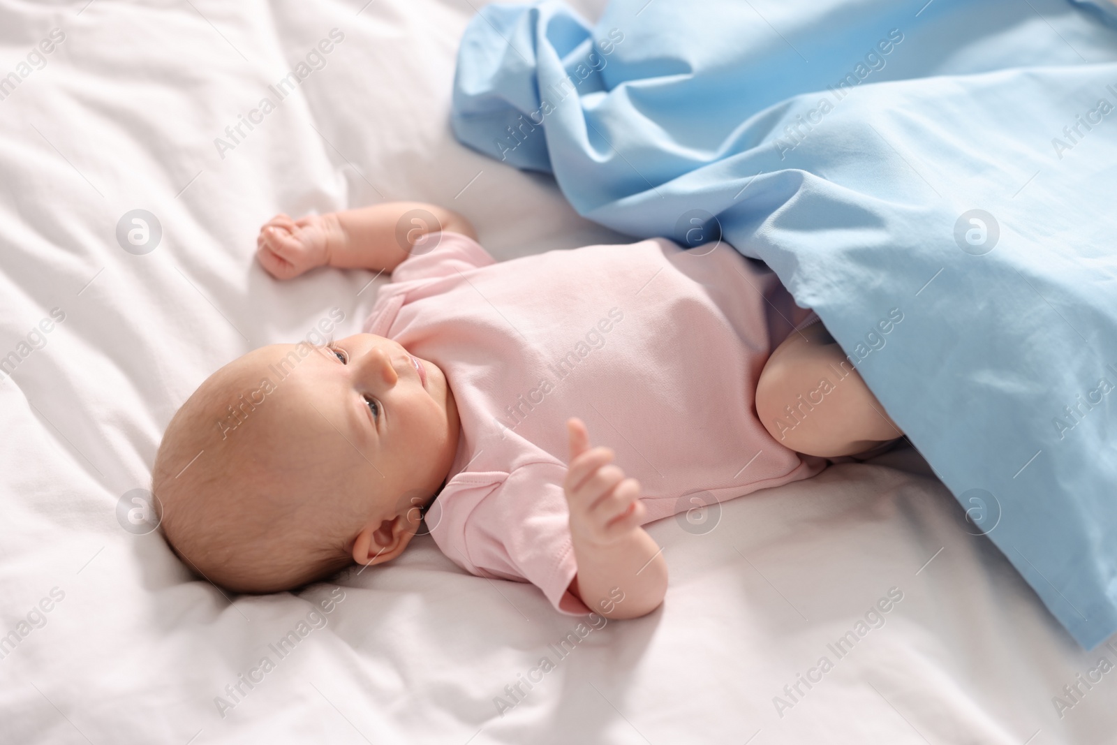 Photo of Cute little baby lying on white sheets