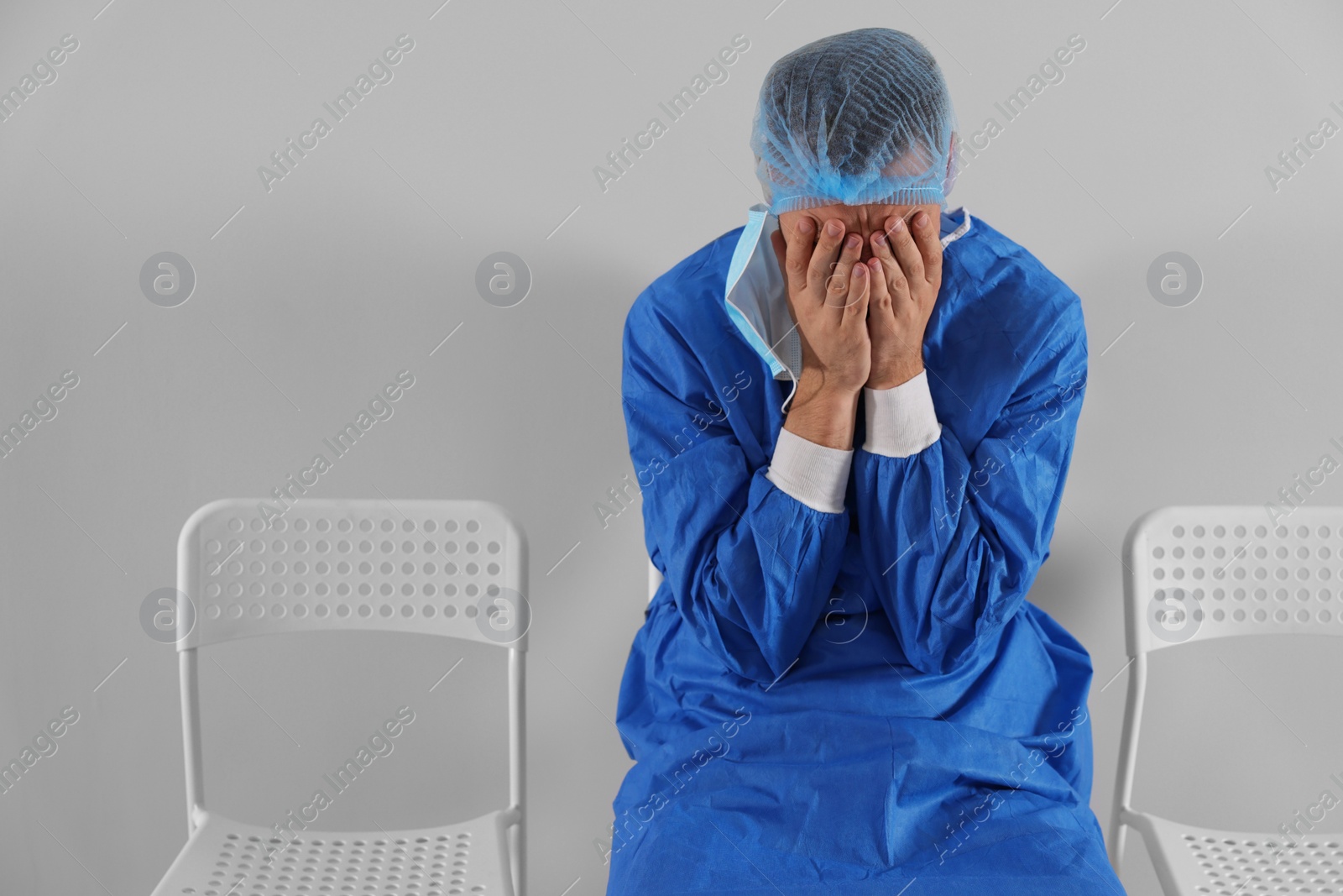 Photo of Exhausted doctor sitting on chair near grey wall, space for text