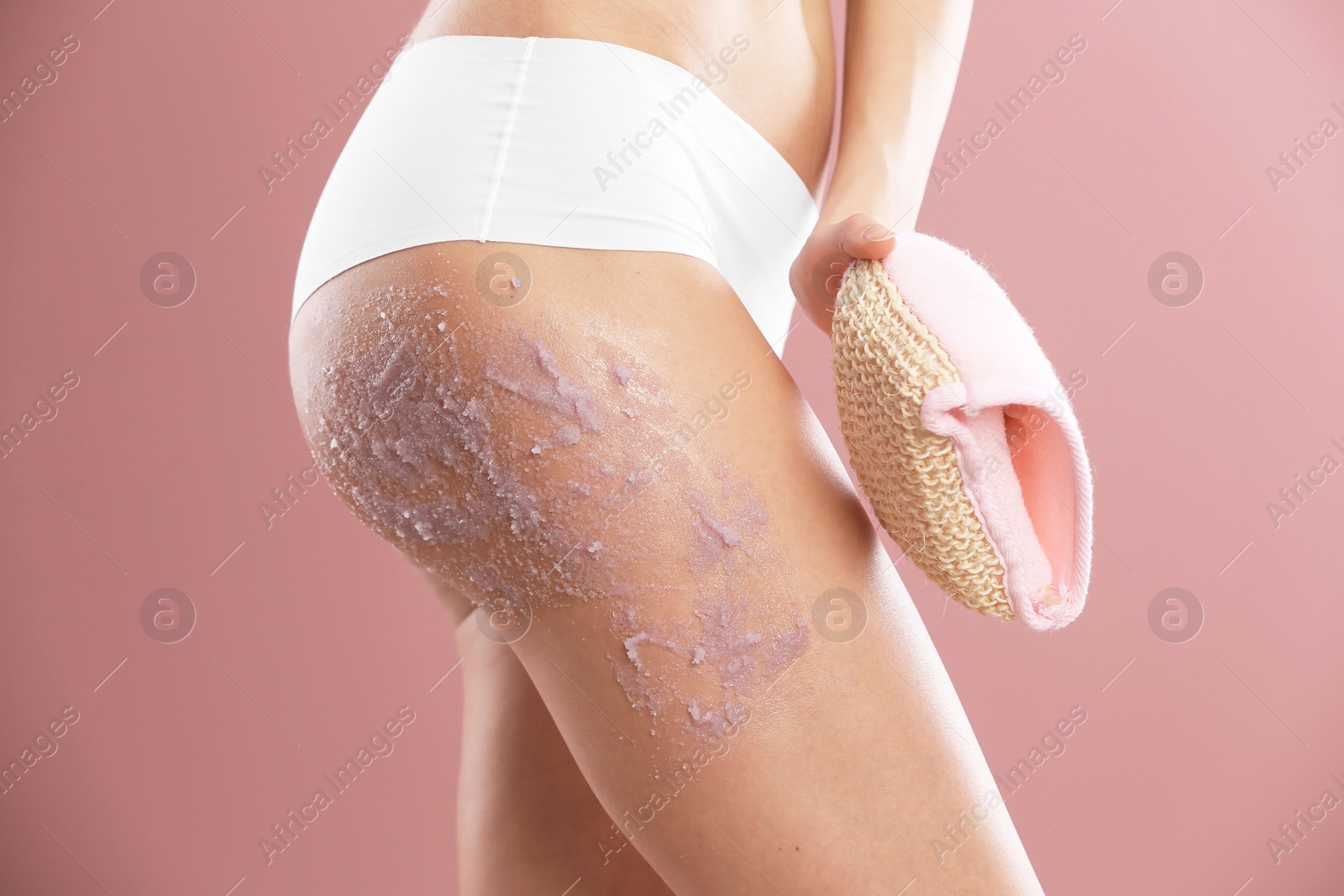 Photo of Young woman applying natural scrub on her body against color background