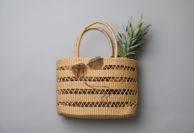 Stylish straw bag and sunglasses on grey background, flat lay. Summer accessories
