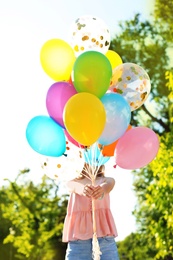 Photo of Young woman with colorful balloons outdoors on sunny day