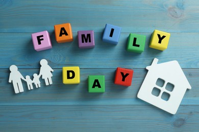 Photo of International Family day. Flat lay composition with cubes. house and people figures on light blue wooden background