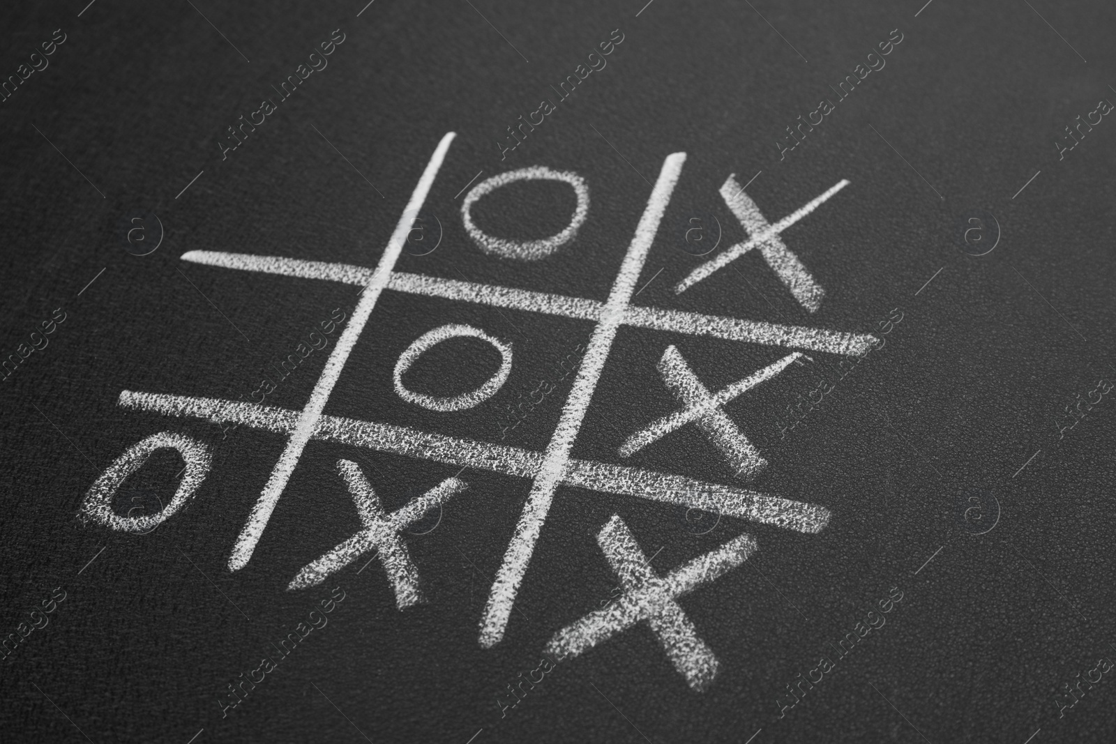 Photo of Tic tac toe game on blackboard, closeup