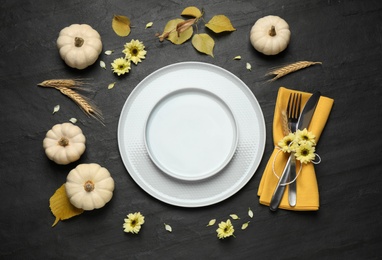 Photo of Festive table setting with pumpkins and flowers on black background, flat lay. Thanksgiving Day celebration