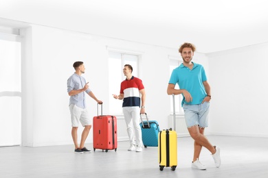 Group of young people with suitcases in light room