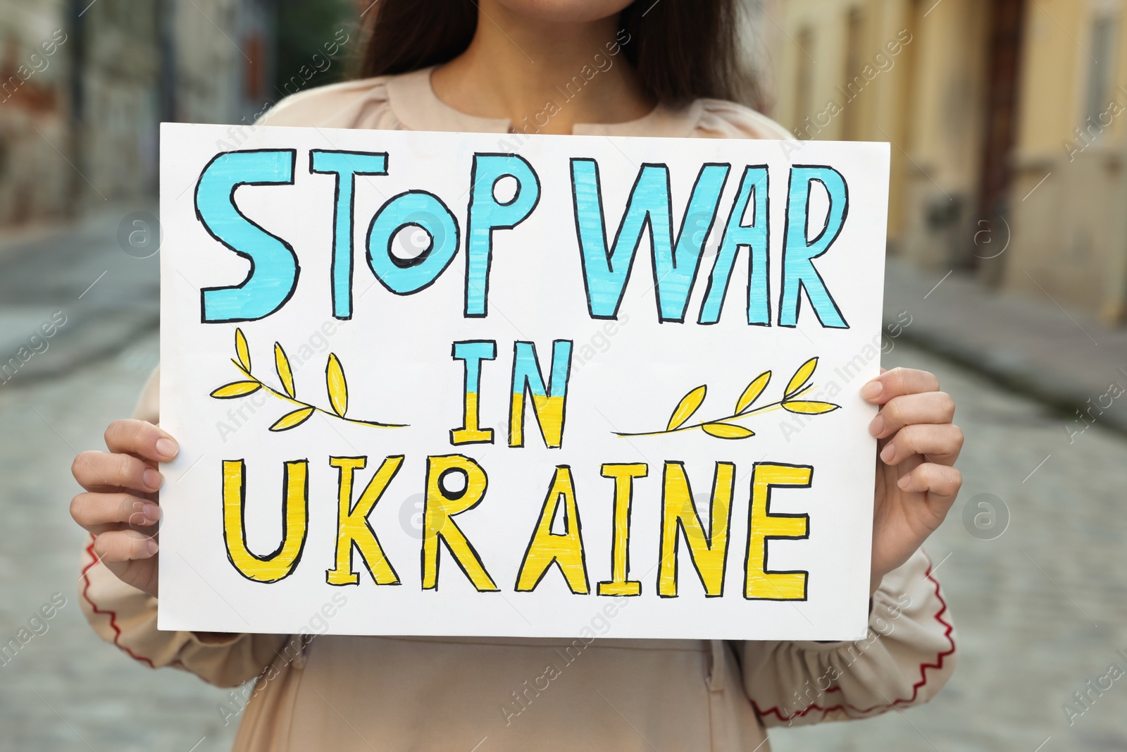Photo of Woman holding poster Stop War in Ukraine on city street, closeup