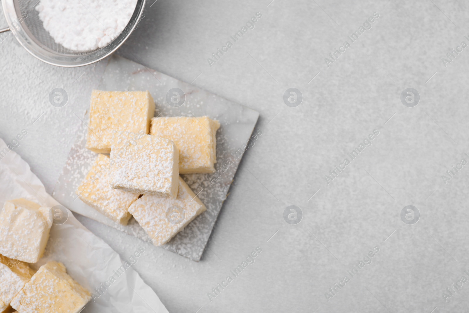 Photo of Delicious sweet marshmallows with powdered sugar on light grey table, flat lay. Space for text