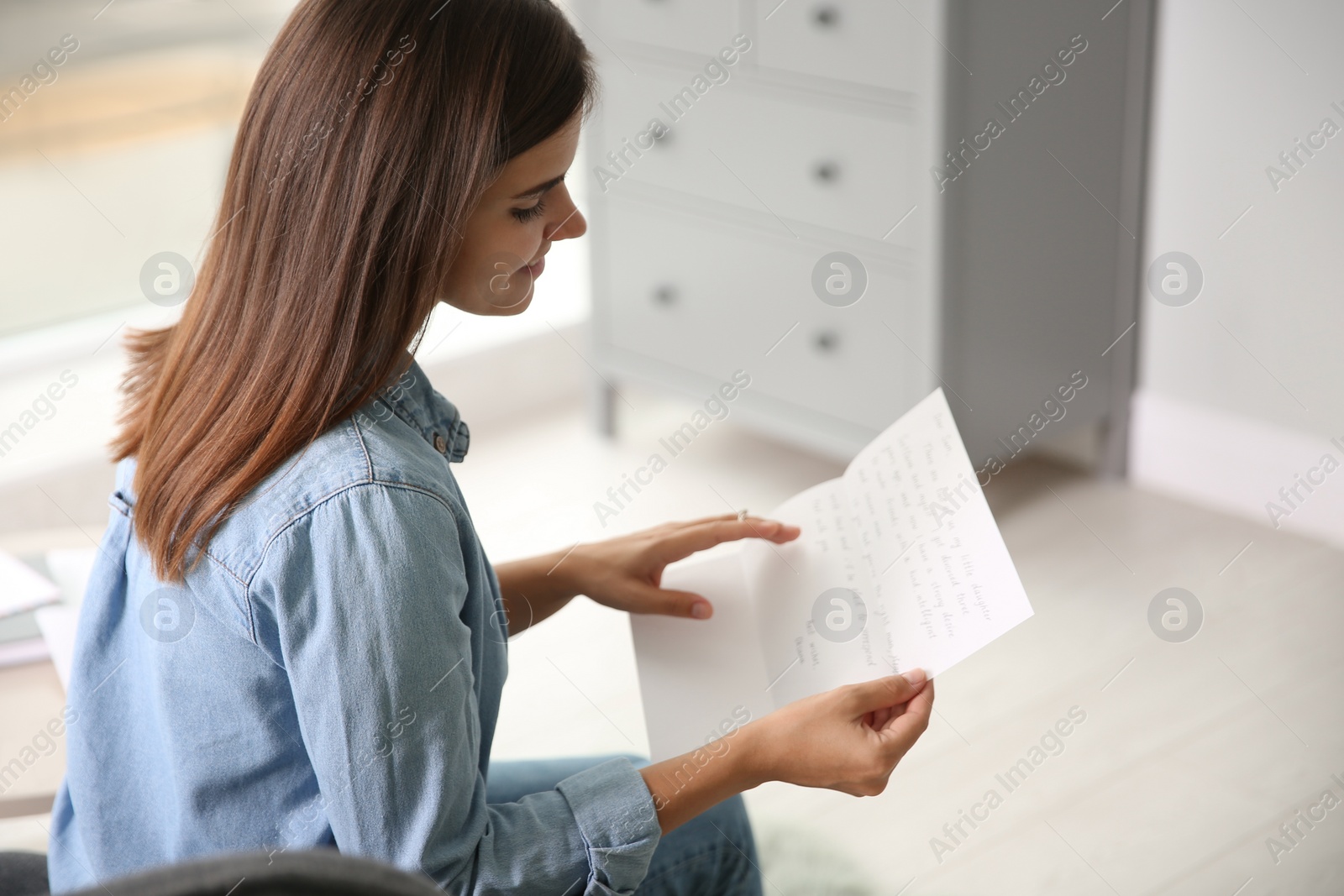 Photo of Young woman reading paper letter at home