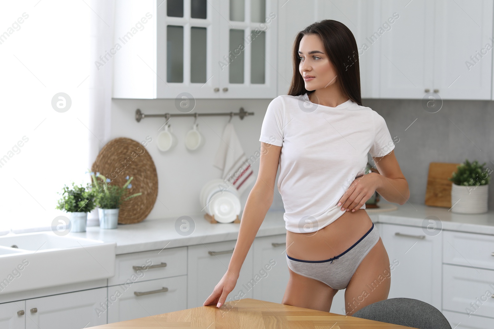 Photo of Young woman in white t-shirt and comfortable underwear indoors. Space for text