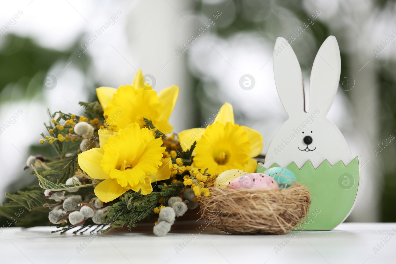 Photo of Festive composition with Easter eggs on table against blurred window