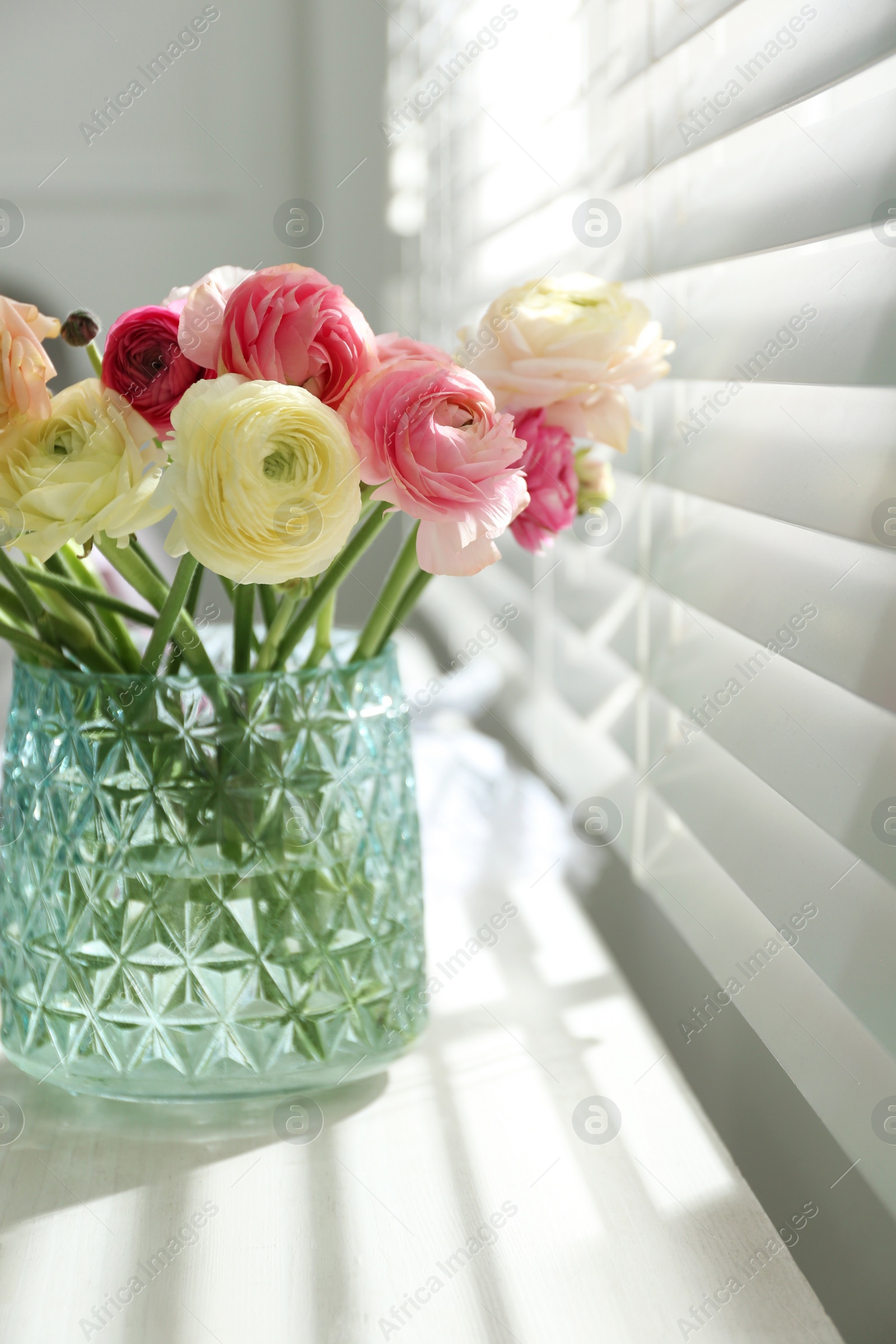 Photo of Beautiful ranunculus flowers in vase on window sill indoors