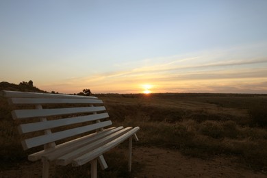 Photo of Wooden bench in field at sunrise. Early morning landscape