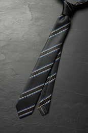 Photo of One striped necktie on grey textured table, top view