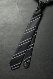 One striped necktie on grey textured table, top view