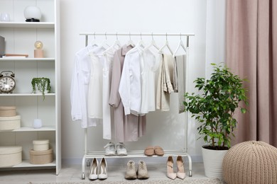 Photo of Rack with different stylish women`s clothes and shoes indoors