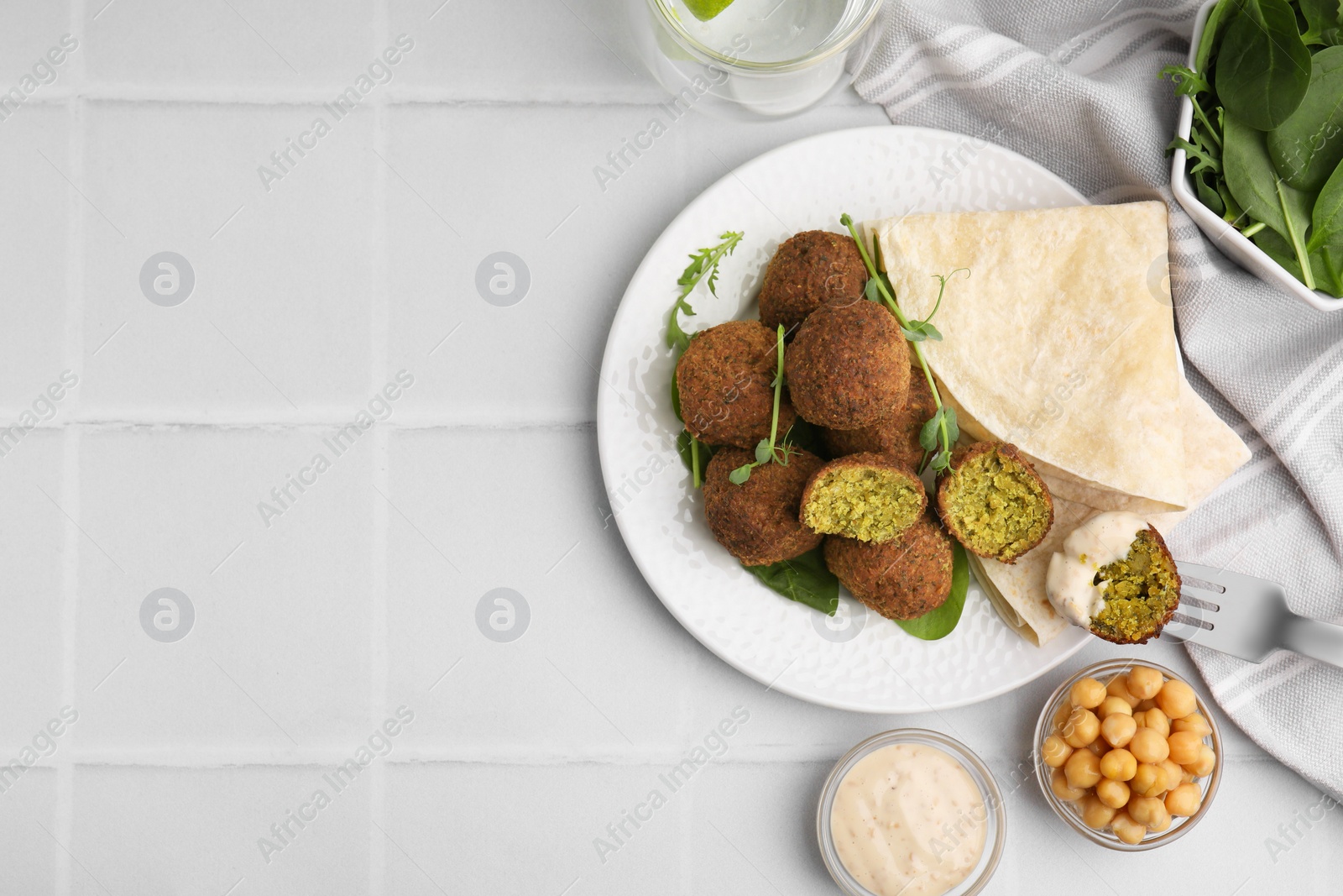 Photo of Delicious falafel balls served on white tiled table, flat lay. Space for text