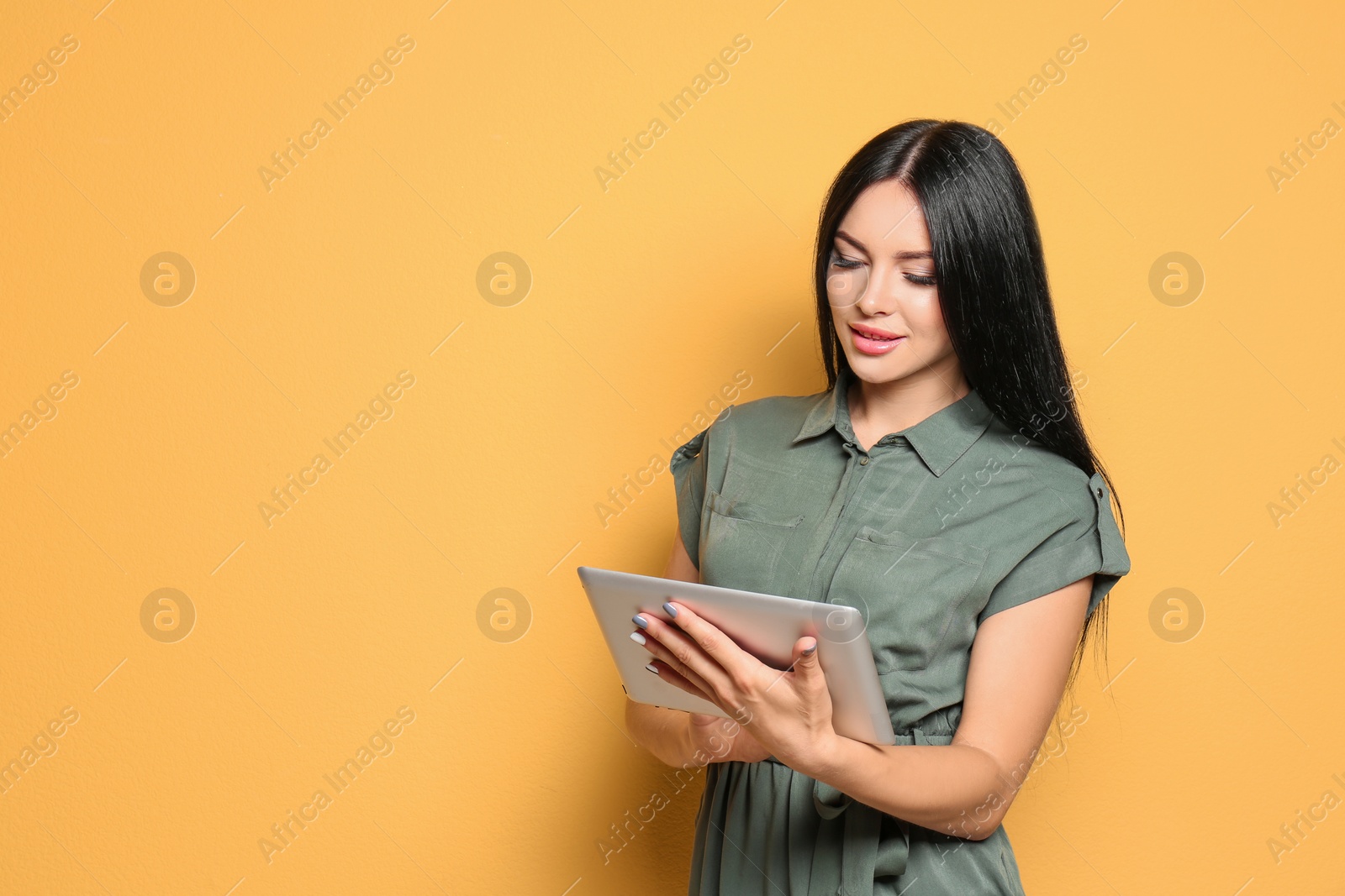 Photo of Beautiful woman with tablet on color background. Space for text