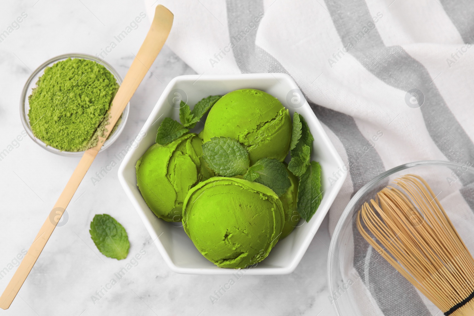 Photo of Tasty matcha ice cream, powder, bamboo whisk and spoon on white marble table, flat lay
