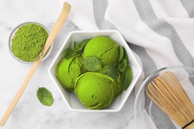 Tasty matcha ice cream, powder, bamboo whisk and spoon on white marble table, flat lay