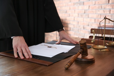 Photo of Judge with papers at table in office, closeup. Law and justice concept