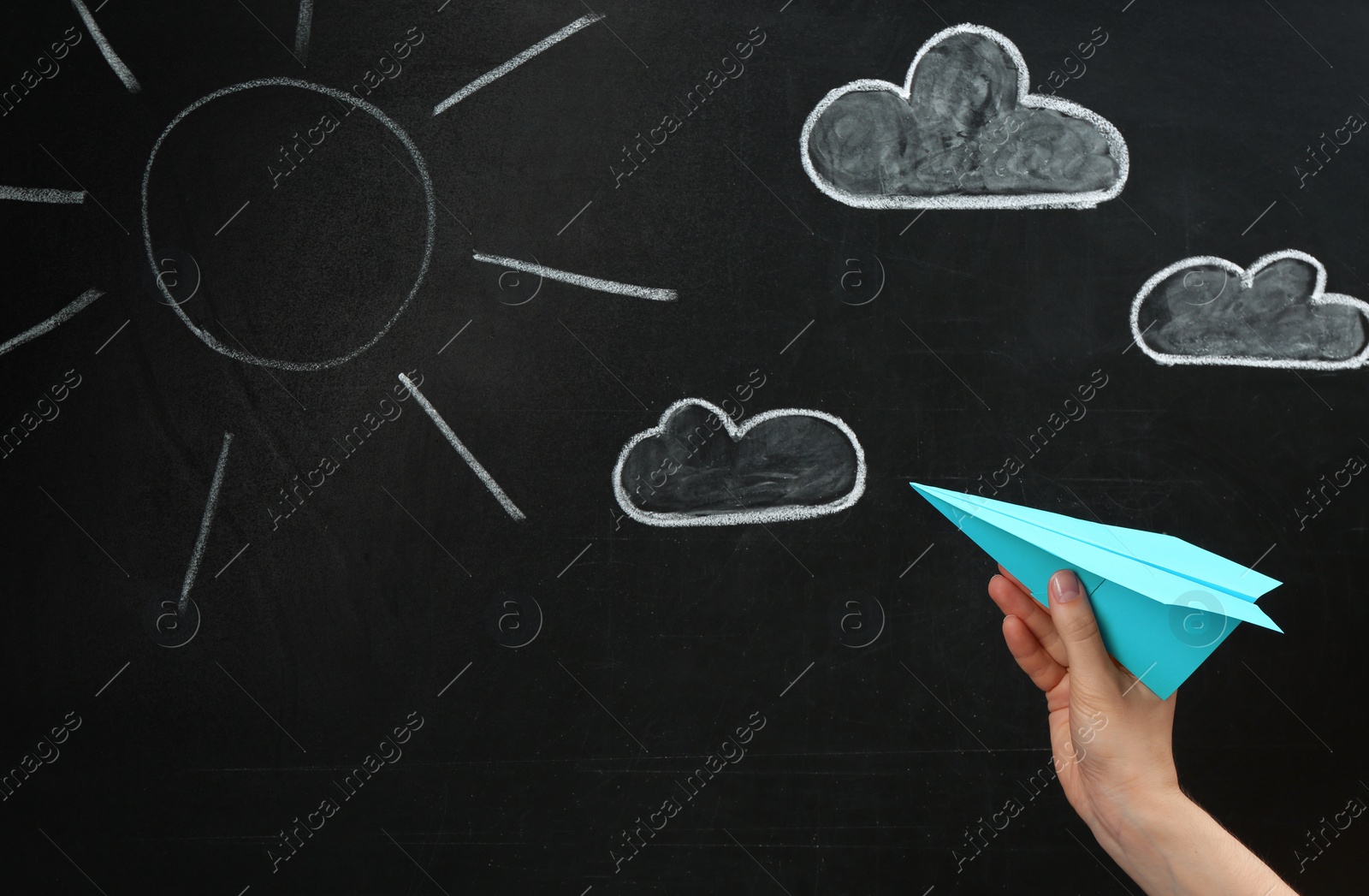 Photo of Woman holding paper plane near blackboard, closeup