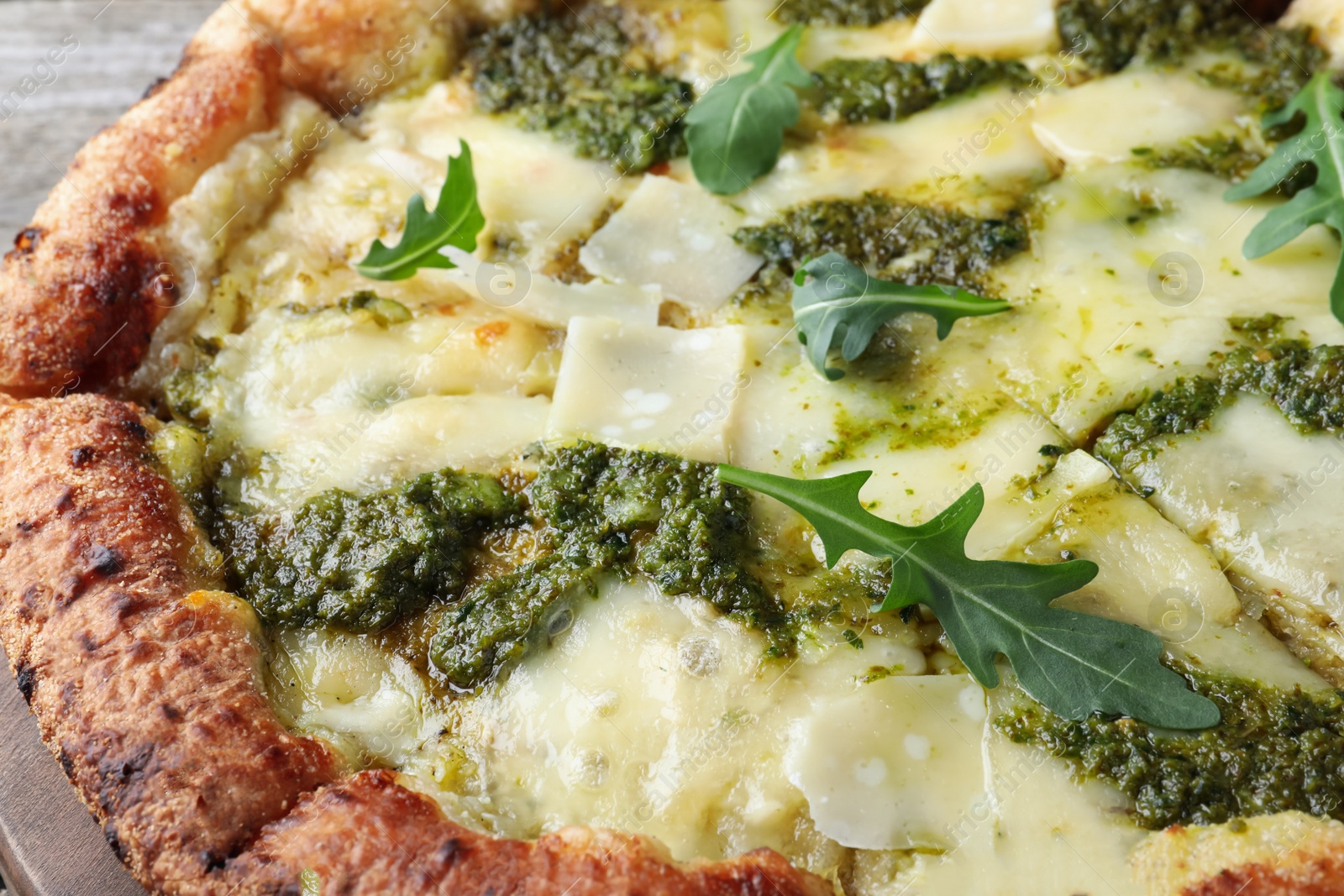 Photo of Delicious pizza with pesto, cheese and arugula, closeup