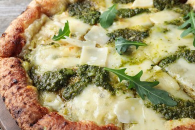 Delicious pizza with pesto, cheese and arugula, closeup