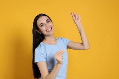 Photo of Young woman snapping fingers on yellow background