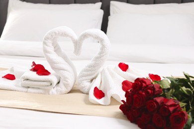 Honeymoon. Swans made of towels and beautiful red roses on bed