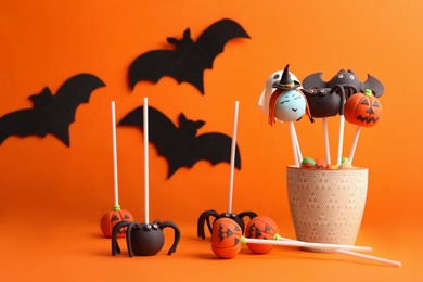 Photo of Delicious Halloween themed cake pops on orange background