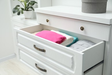 Photo of Chest of drawers with different folded clothes indoors