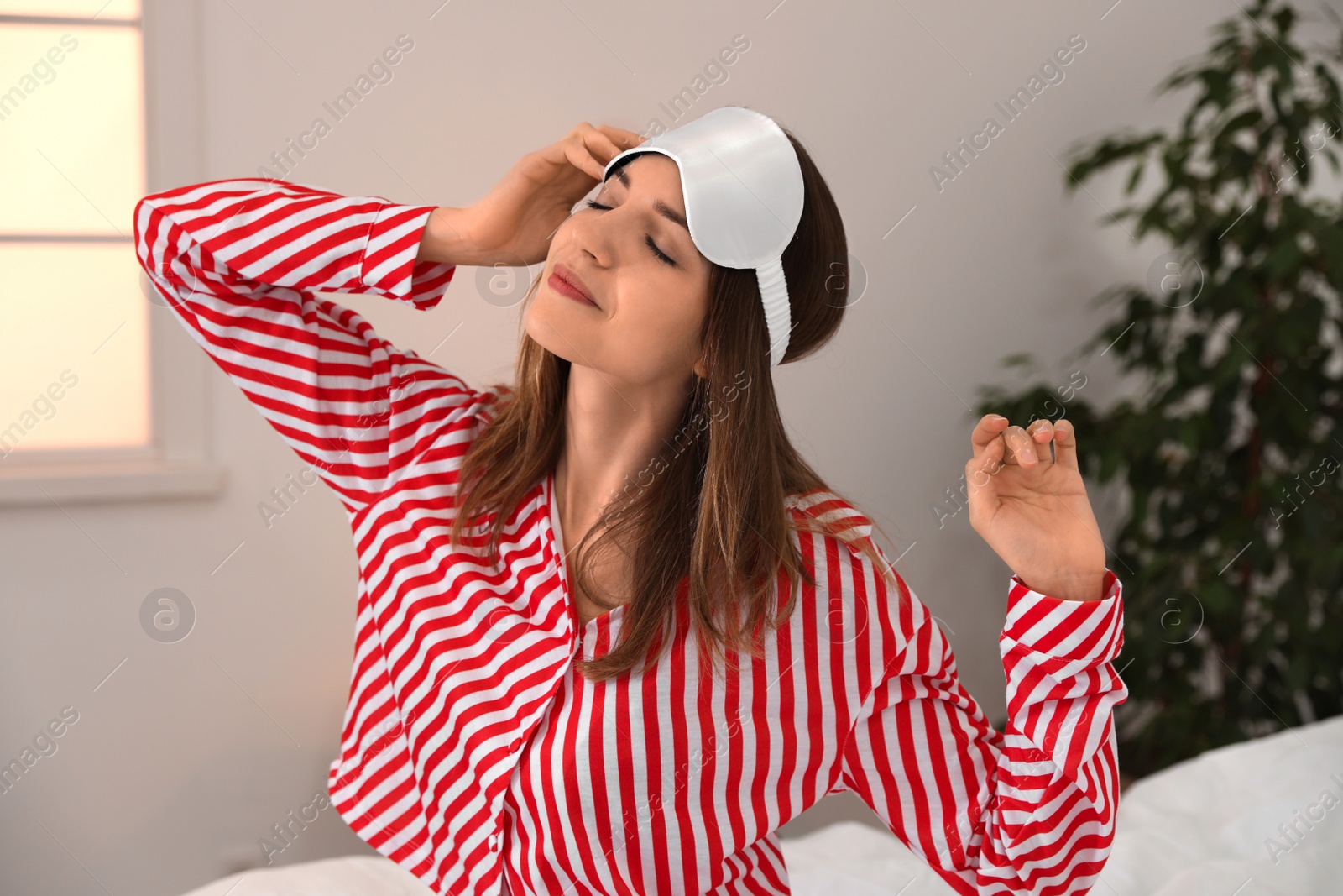 Photo of Beautiful woman wearing pajamas and sleep mask indoors. Bedtime